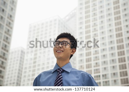 Young businessman smiling and looking at the sky