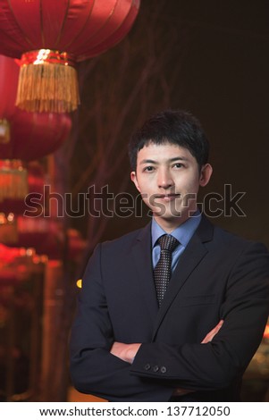 Businessman standing on the street, red lanterns on the background