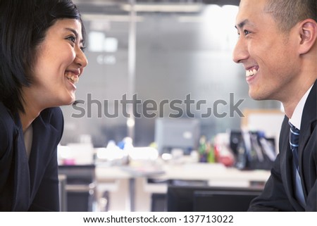 Two business people smiling and laughing face to face