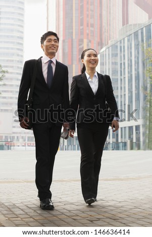 Two young business people walking outdoors, Beijing, China