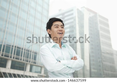 Portrait of young businessman in button down shirt with arms crossed, outdoors, Beijing