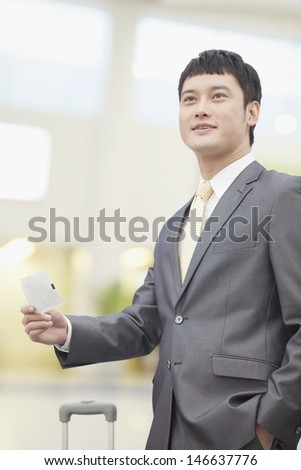Smiling business man holding flight ticket
