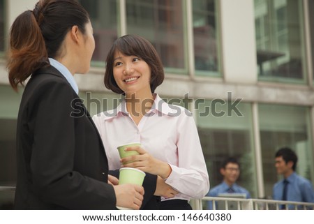Businesswomen talking and drinking coffee outdoors