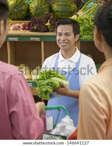 Sales clerk assisting couple in supermarket, Beijing
