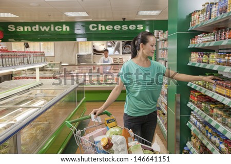 Woman reaching for jar on the shelf in the supermarket, Beijing