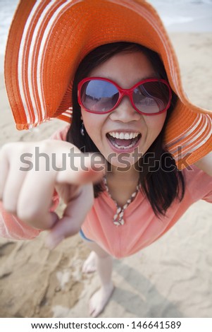 Smiling women standing on the beach pointing at camera, portrait