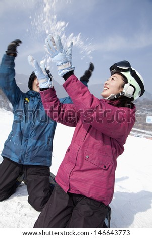Young Man and Woman Playing in the Snow in Ski Resort