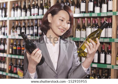 Mid Adult Woman Choosing Wine in a Liquor Store
