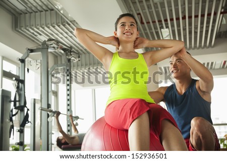 Young women exercising with her personal trainer in the gym