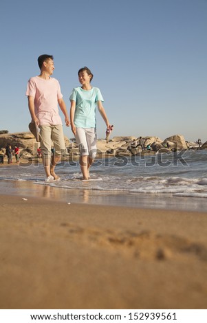 Father and Daughter walking along the waters edge, beach, China
