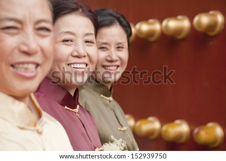 Group of mature women in traditional clothes standing next to the traditional Chinese door
