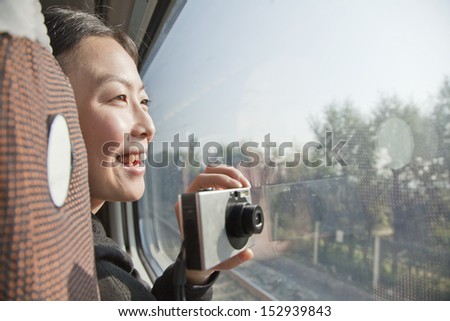 Young Woman Taking Photographs Outside Train Window