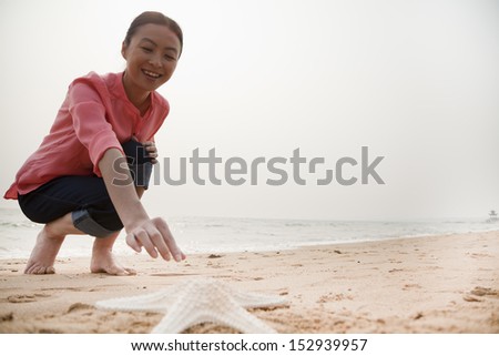Young Woman Reaching Out for Starfish