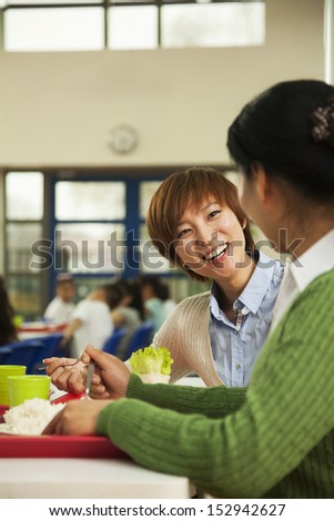 Teachers talking at lunch in school cafeteria