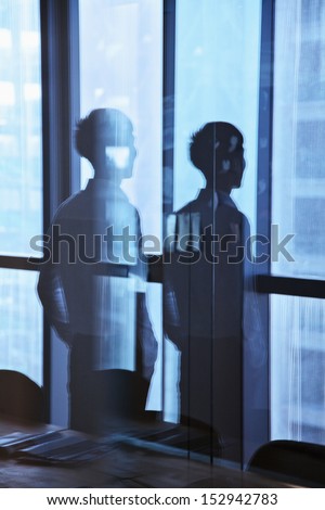 Reflection of businessman looking outside the window