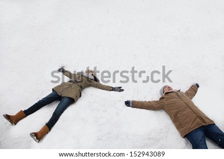 Young couple laying in snow making snow angels