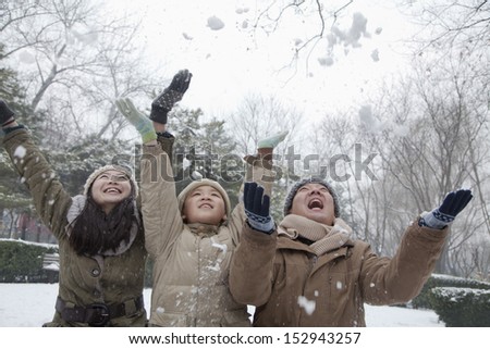 Family throwing snow into air in park