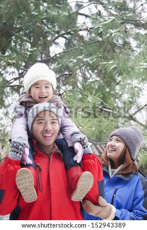Father carrying daughter on shoulders in winter