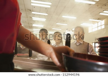 School cafeteria worker serves noodles to students