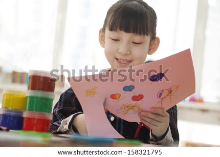 Schoolgirl cutting out drawing in class