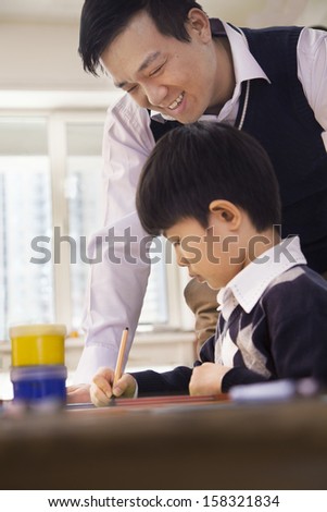 Teacher helping schoolboy with arts and crafts