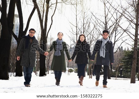 Couples holding hands in park covered in snow