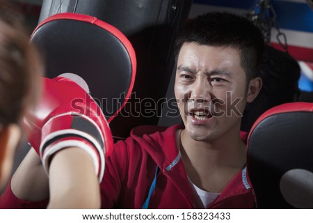 Boxing couch training with female student holding boxing pads