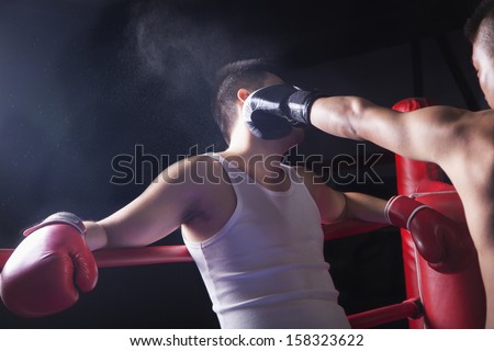 Male boxer throwing knockout punch in the boxing ring