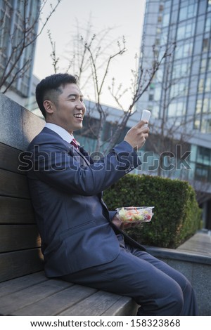 Smiling businessman on lunch texting on his mobile phone