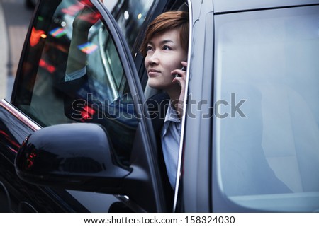 Businesswoman exiting car while on the phone
