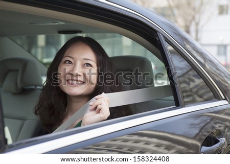 Young women in back seat of car fastening seat belt.