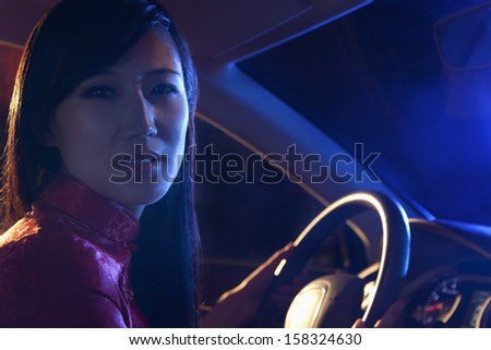 Portrait of young, beautiful woman in traditional clothing driving at night