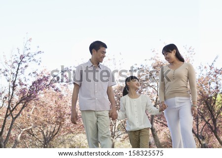 Happy family holding hands and taking a walk amongst the cherry trees
