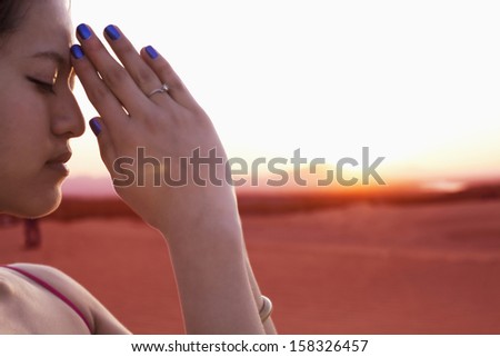 Serene young woman with eyes closed and hands together in prayer pose