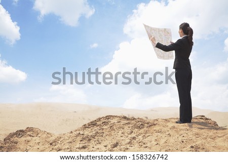 Young Businesswoman looking at map in the middle of the desert