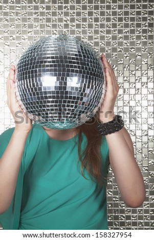 Young woman holding disco ball in front of her face