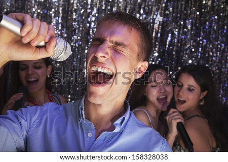 Young man singing into microphone at karaoke