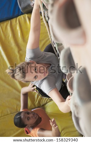 Two young women climbing in an indoor climbing gym