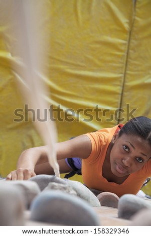 Young woman climbing up a climbing wall in indoor climbing gym