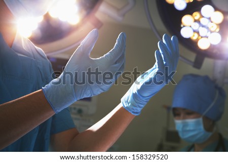 Midsection view of hands in surgical gloves