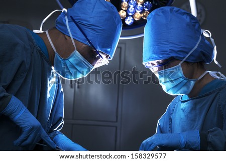 Two Surgeons Working And Concentrating At Operating Table