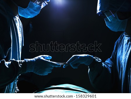 Two surgeons working and passing surgical equipment in the operating room