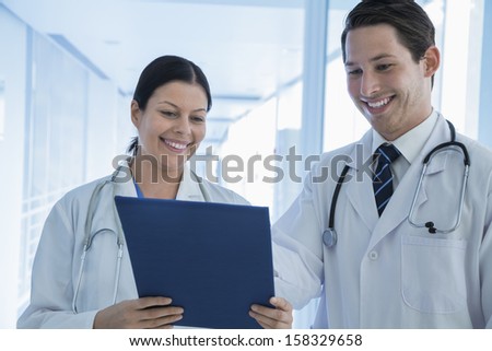 Two smiling doctors looking down at a medical record in the hospital