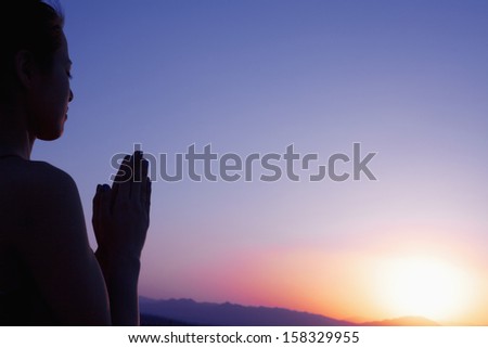 Serene young woman with hands together in prayer pose in the desert in China
