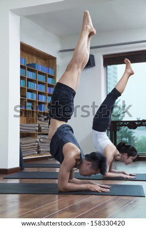 Two people with legs raised doing yoga in yoga studio