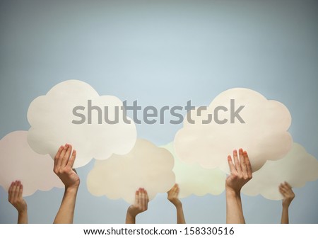 Multiple hands holding cut out paper clouds against a blue background