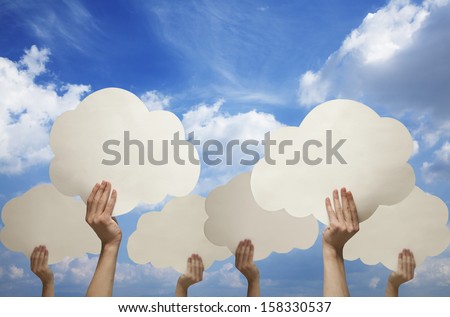 Multiple hands holding cut out paper clouds against blue sky with clouds