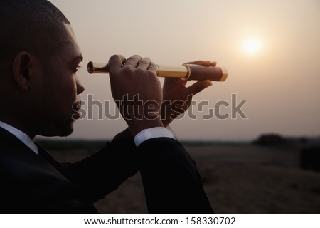Young Businessman Looking Through Telescope In The The Desert