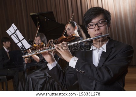 Flautist holding and playing the flute during a performance