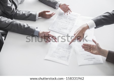 Four business people arguing and gesturing around a table